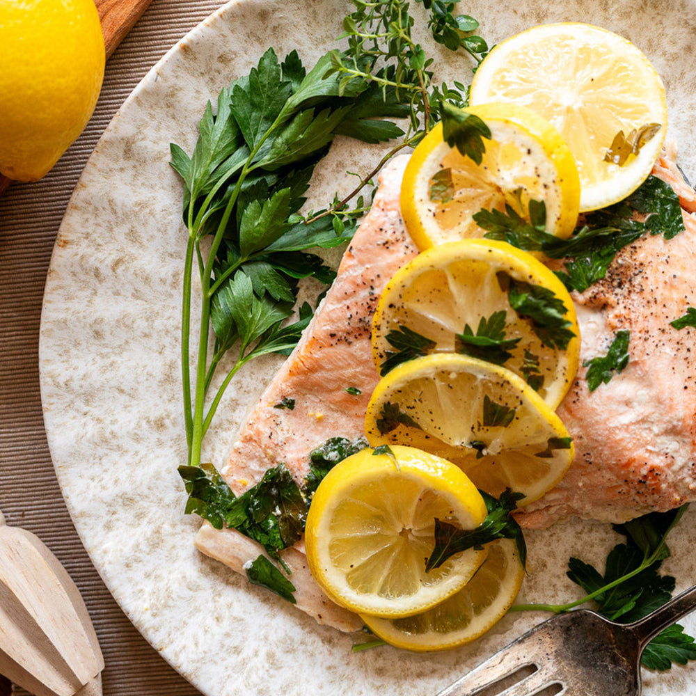 Salmon dish with lemon slices and herbs on a stone plate