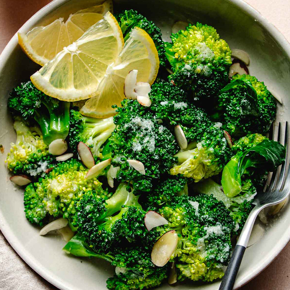 Broccoli salad with lemon slices and almonds on a white plate