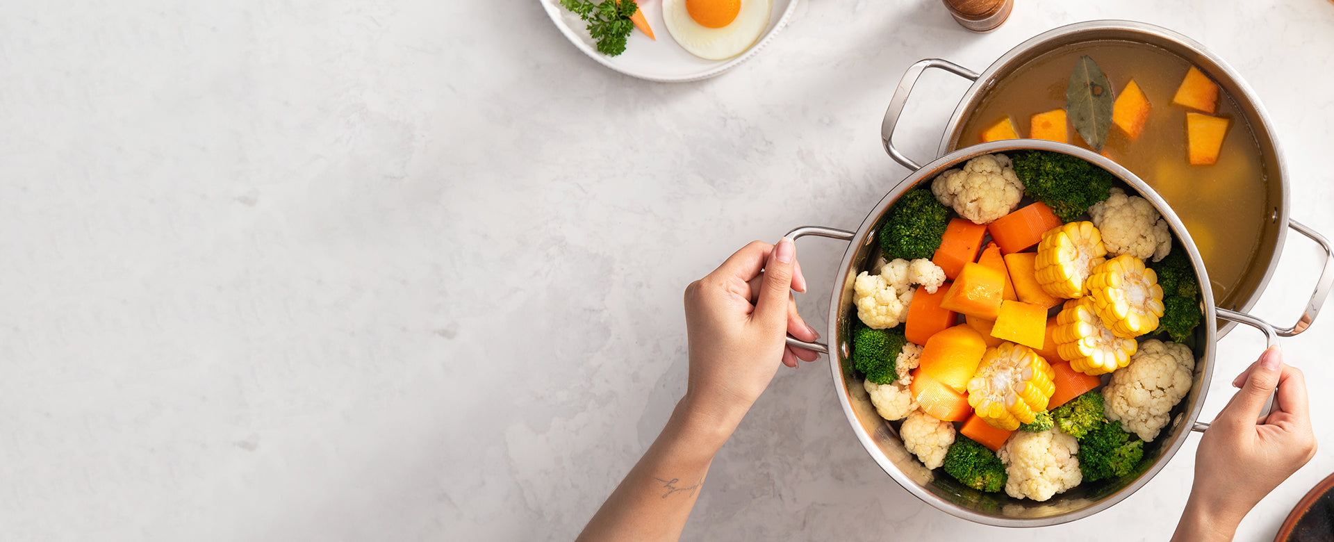 Person holding a pan of vegetables on a light gray surface
