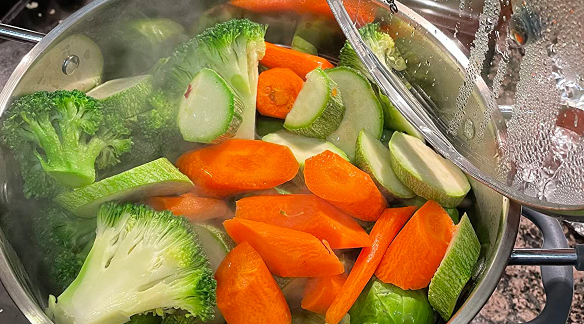 Vegetables including broccoli and carrots in a Sunhouse pot with steam rising.