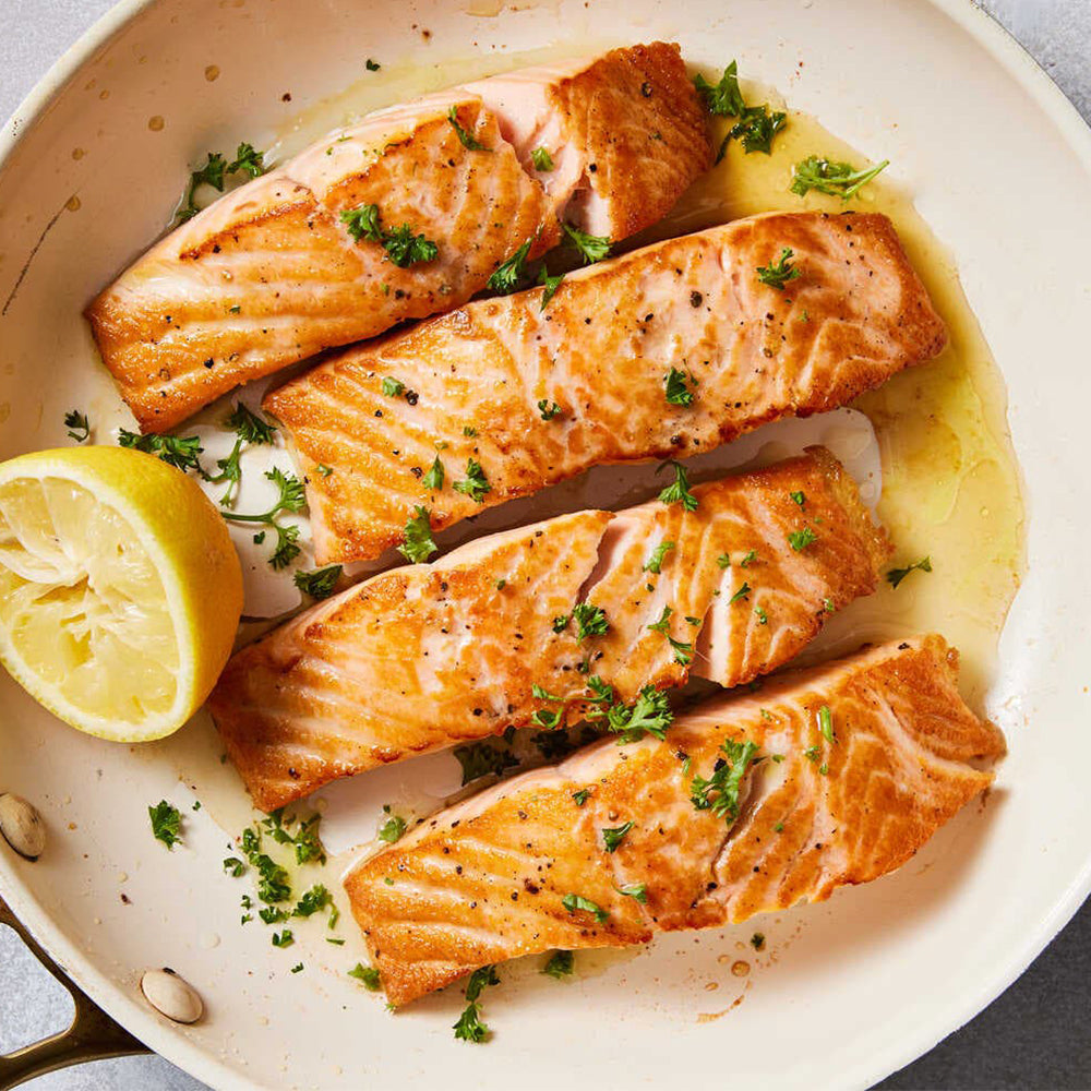 Seared salmon fillets with lemon and herbs in a pan
