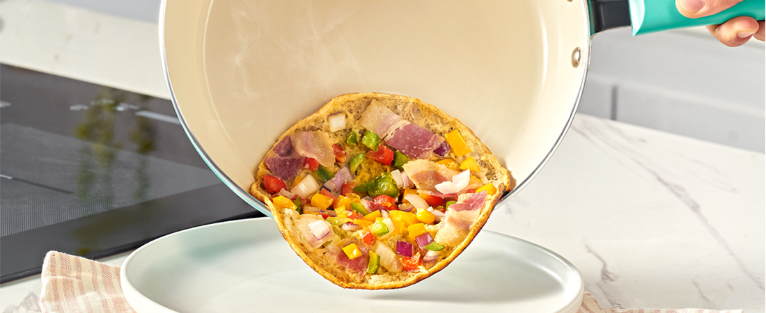 Colorful pizza being lifted from a Sunhouse pan with a spatula