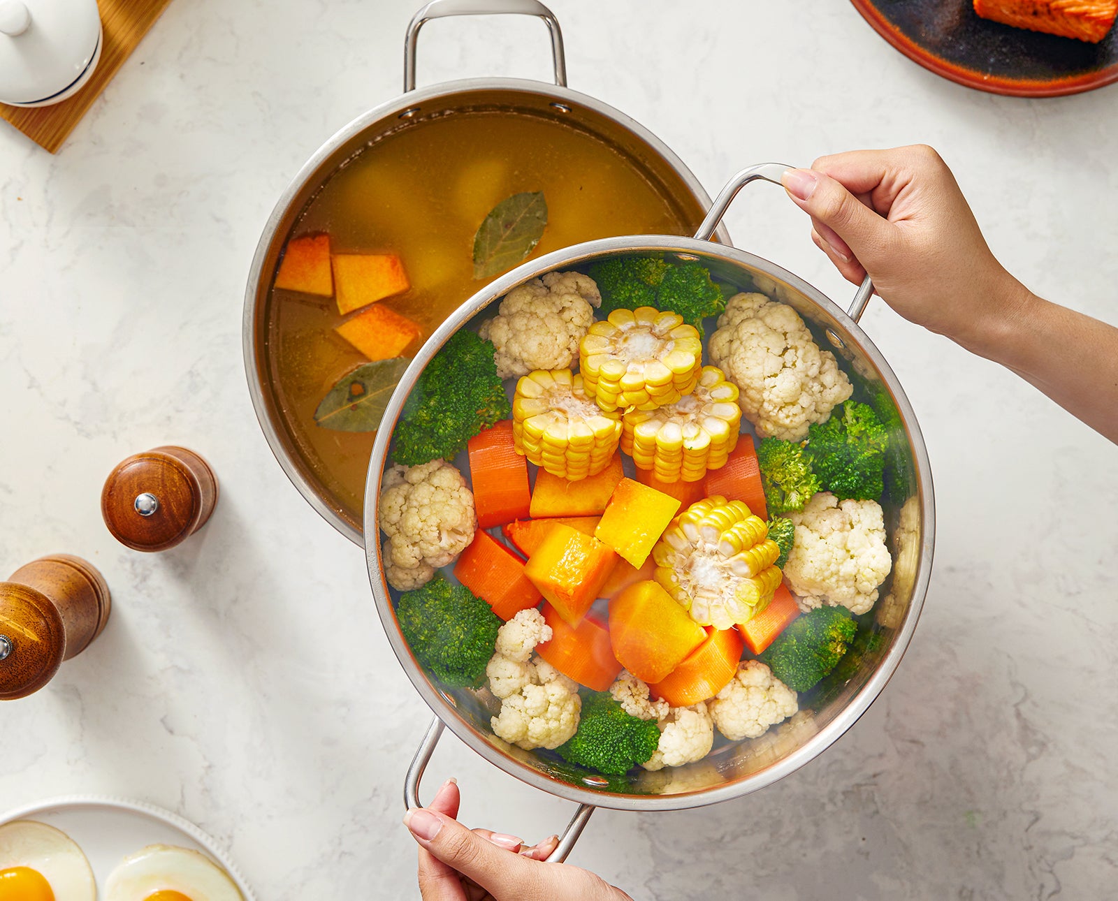 Two pots filled with a colorful assortment of vegetables on a light gray surface.