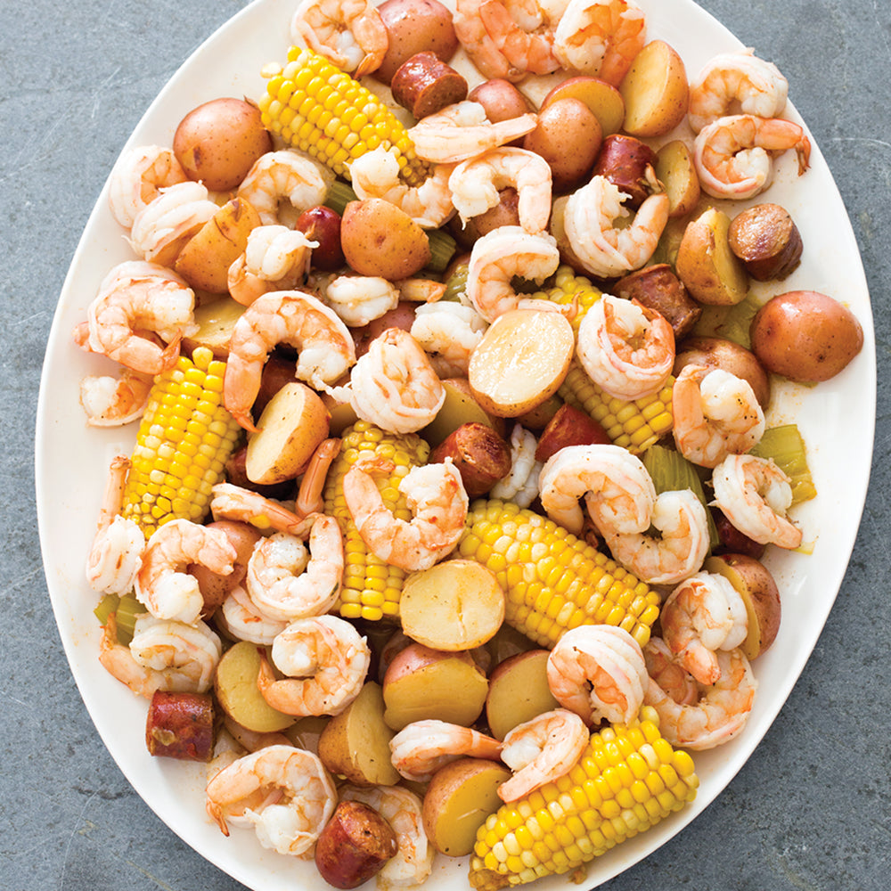 Platter of shrimp, corn, and potatoes on a gray surface